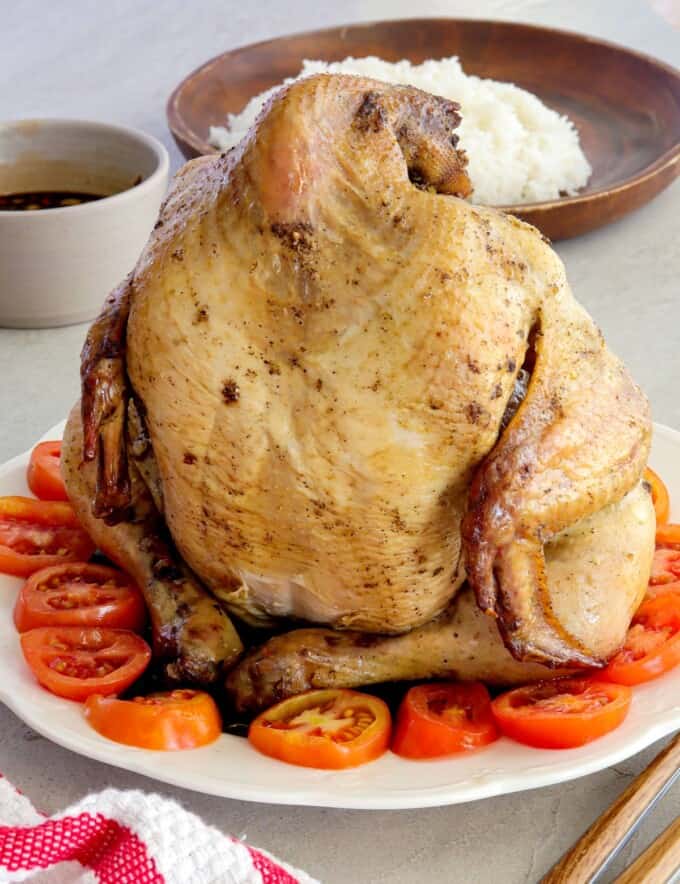 Pinaupong Manok on a white serving platter over sliced tomatoes.